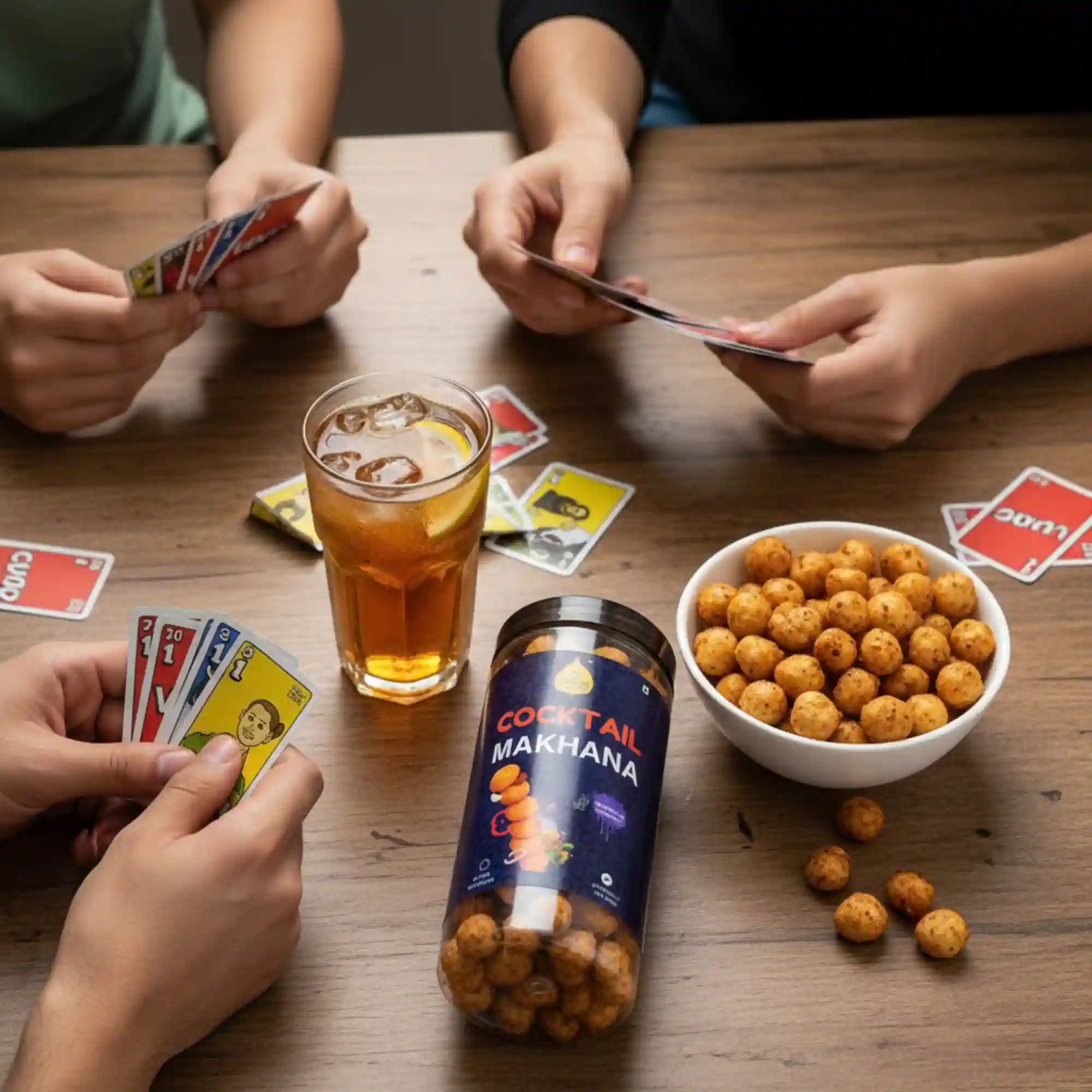 cocktail-makhana-social-snacking-lifestyle Friends playing cards and sharing a bowl of Health Ratna Cocktail Makhana with drinks